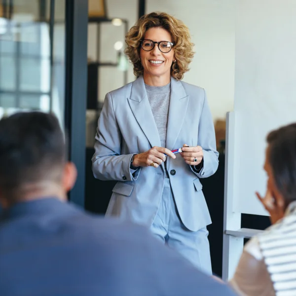 A woman wearing glasses presents to her colleagues, sharing insights on lead generation strategies and techniques.