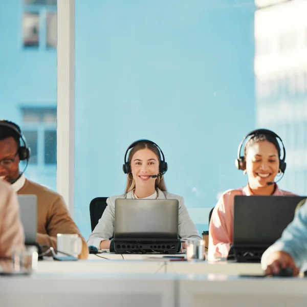 A diverse group of professionals engaged in communication at a busy call center, showcasing a collaborative work environment.