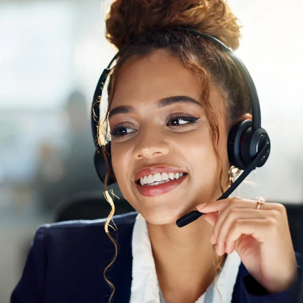 A woman in a headset smiles, embodying professionalism and positivity in a contact center environment.